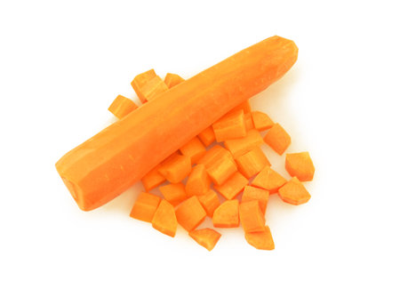 A peeled, whole carrot placed next to a scatter of freshly diced carrot cubes, viewed from above on a clean white background. High quality photoの写真素材