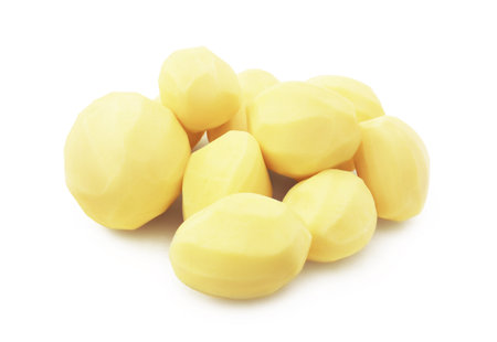 An overhead view of a group of whole, raw, yellow potatoes that have been freshly peeled, scattered on a white background. High quality photoの写真素材