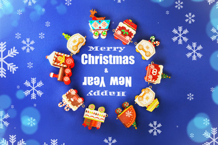 Merry Christmas Happy New Year text surrounded by colorful festive toy train carriages on a snowy blue background.の写真素材