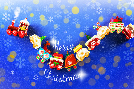 Merry Christmas text surrounded by a curved toy train carrying gifts and festive decorations on a snowy blue background. High quality photoの写真素材