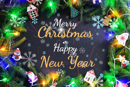 A festive composition with "Merry Christmas Happy New Year" text framed by fir branches, colorful lights, and holiday ornaments. High quality photoの写真素材