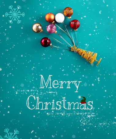 A gold miniature Christmas tree figure flying up with colorful ornaments as balloons on a teal blue background with snowflakes. High quality photoの写真素材