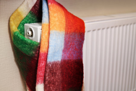 a radiator wrapped in a multi-colored scarf, symbolizing the cold in the room. High quality photoの写真素材