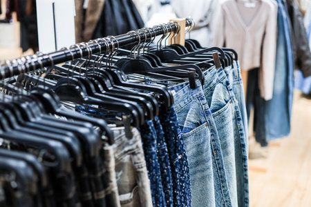 Rack of blue denim jeans hanging in a clothing store, featuring various washes and styles in a modern retail setting. High quality photoの写真素材