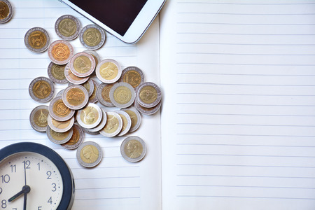 coins, clock and smart-phone put on the notebook.の写真素材