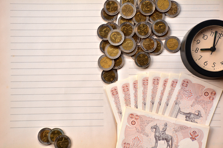 Coins, clock and old ten baht bill put on notebook.の写真素材