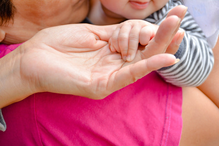 Baby smile and hand of adult and hand of baby touch togetherの写真素材