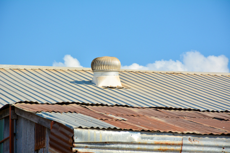 Rusty roofing iron and ventilated roof under the blue skyの写真素材