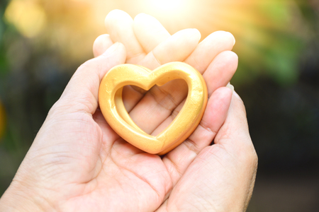Valentines day Hands of person holding wood heart under the sunlightの写真素材