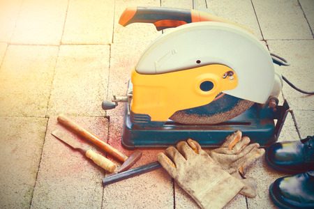 The cutting tool, gloves, hammer, chisel and shoes put on brick under the sunlight vintage style