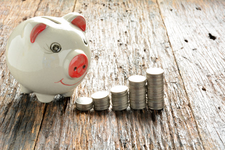 Finance stack coins and piggy bank on wood tableの写真素材