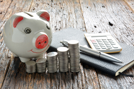 Finance stack coins and piggy bank on wood tableの写真素材