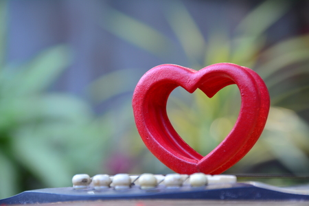 Red wood heart put on guitar for love on nature background