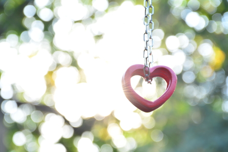 Red wood heart and chain for love on sunlight and nature backgroundの写真素材