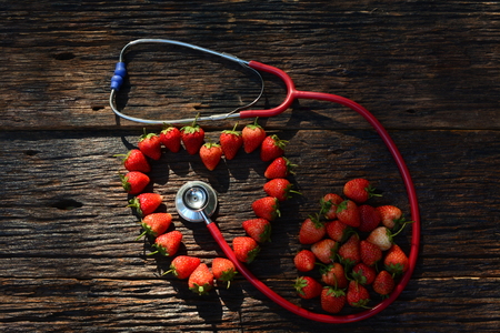 stethoscope and strawberry heart for healthy on old wood bark backgroundの写真素材
