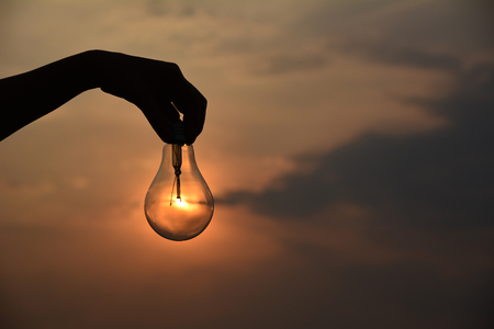hand holding light bulbs idea concept and silhouette style under the skyの写真素材