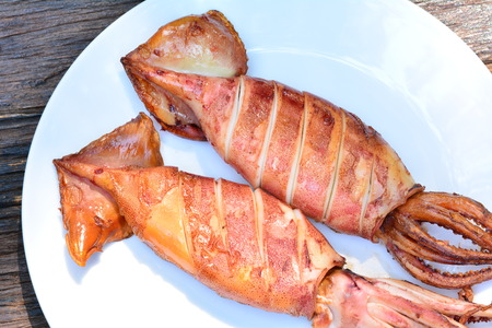 Grilled squid on white plate on wood table,sea food of Thailandの写真素材