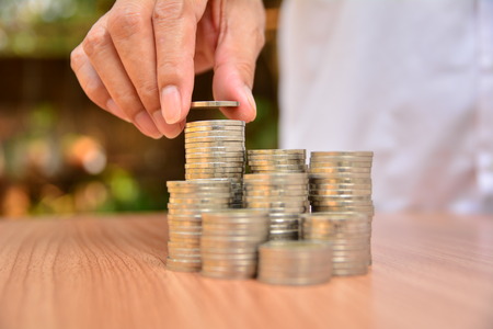 Saving money concept and hand putting money coin stack growing for business