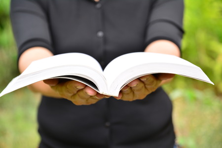 Hands of person hold the book on nature backgroundの写真素材