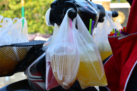 plastic bag with sweet drinks with ice with motorcycle. の写真素材