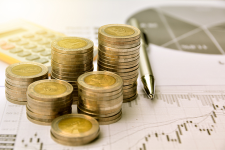 money coins with graph paper and calculator, finance and growth of businessの写真素材