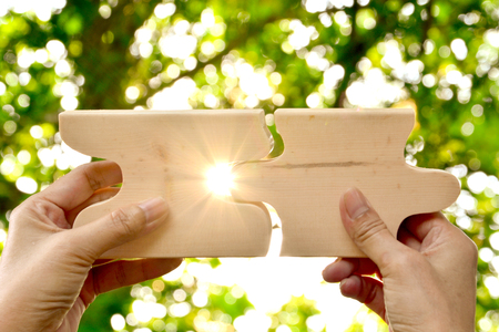 hand holding wood jigsaw piece texture pattern on nature backgroundの写真素材