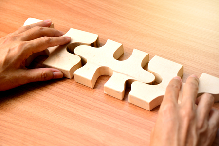 hand holding wood jigsaw piece texture pattern on wood table backgroundの写真素材