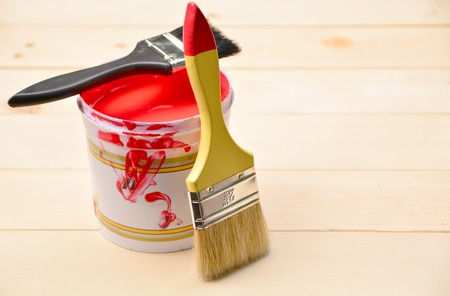 two paintbrush and paint can and with red color on wooden table.の写真素材