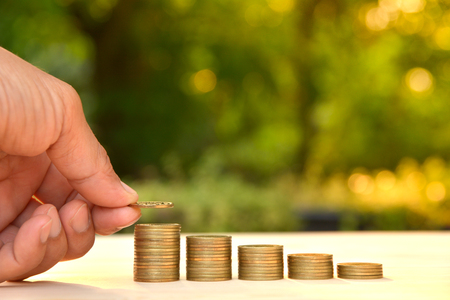 Saving money concept and hand putting money coin stack growing for businessの写真素材