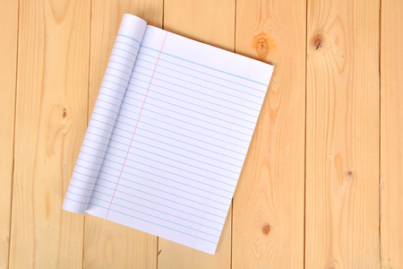 Notebook open to show white paper on wooden background.の写真素材