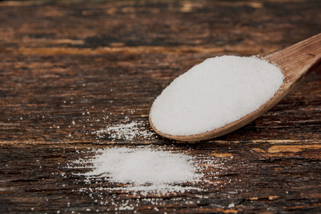 Sugar on a wooden spoon on wooden table の写真素材