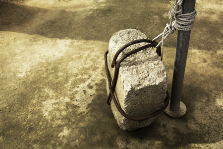 Stone tied to a iron pole on old cement groundの写真素材