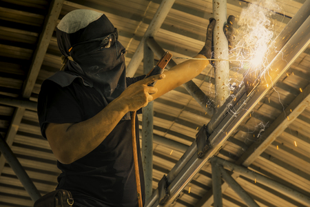 Industrial Worker at the factory steel welding under the roof.
