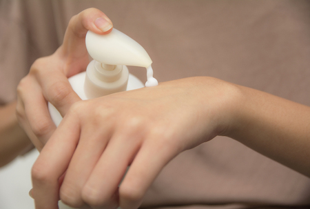 hand of woman apply lotion on skin of back hand.の写真素材