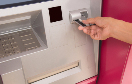 Hand of a woman with a credit card, using an ATM. Woman using an ATM machine. Woman using her credit card on ATM.の写真素材