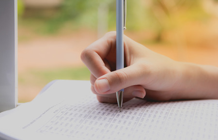 Woman sitting and holding a blue pencil and doing an examの写真素材