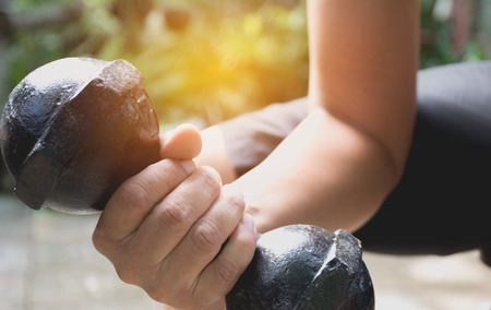Hand of person holding dumbbell for exercise and healthy under the sunlight.の写真素材