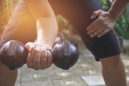 Hand of person holding dumbbell for exercise and healthy under the sunlight.の写真素材