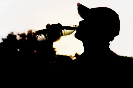 Close up of a man drinking water from a bottle after exercise. Portrait of a man drinking a water outside.の写真素材