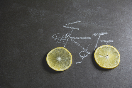 lemon slice shape wheel of bicycle paint by chalk on black table background.の写真素材