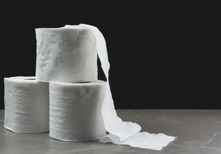 Close-up image stack of toilet papers roll on the table with dark background.の写真素材