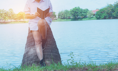 woman reading a book enjoys of rest. Woman hand holding a book for read. Concepts of rest and comfort.の写真素材