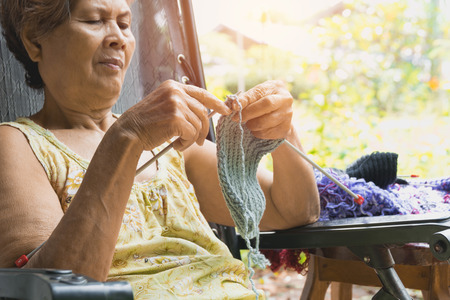 The old woman knits woolen clothes. Close-up of hands knitting. Knitting needles. 