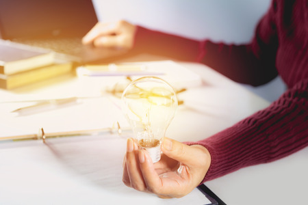 Innovation or creative concept of hand hold a light bulb with laptop.