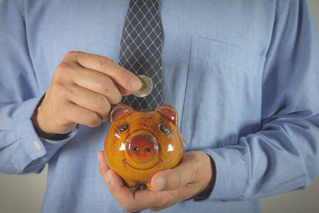 Hand of businessman drop the coin into piggy bank. Financial and saving concept.の写真素材