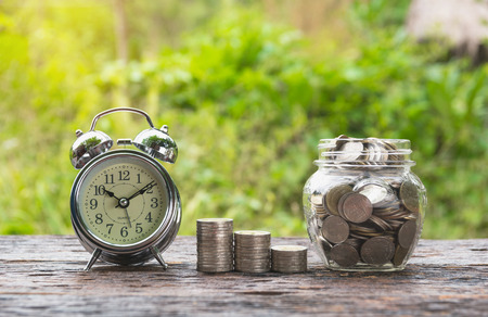 Coins in jar with money stack step growing money and alarm clock, Concept finance business and saving investment.の写真素材