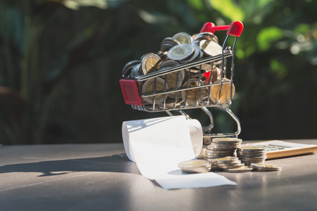 Coins in shopping cart with money stack and bill, Concept finance business and shopping investment.の写真素材