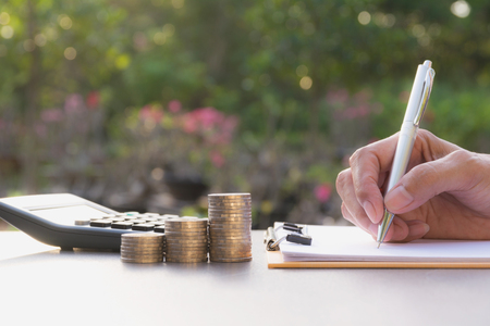 Businesswoman process with stack coins and alarm clock. Businesswoman working the project on table. Financial and accounting concept.の写真素材