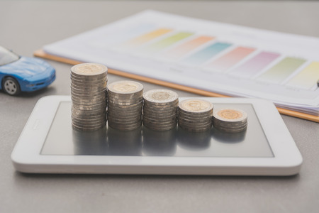 Saving money concept and money coin stack on smart phone with toy car for growing business concept.の写真素材