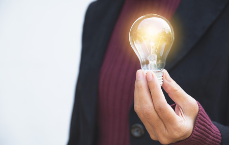 Hand of businesswomean holding light bulb for idea or success or solar energyの写真素材